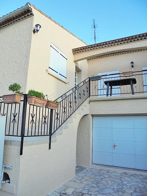 Façades Ariégeoises avec escalier, jardinières et balustrade décorative.